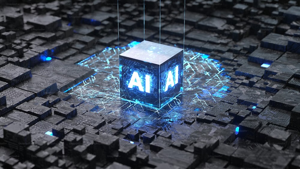 Rendering 3D di un cubo metallico con la scritta "AI" illuminata in blu neon, sospeso sopra una scheda a circuiti integrati di colore grigio scuro, con punti luce blu che si irradiano intorno al processore centrale - realizzazione siti web con Ai conversazione